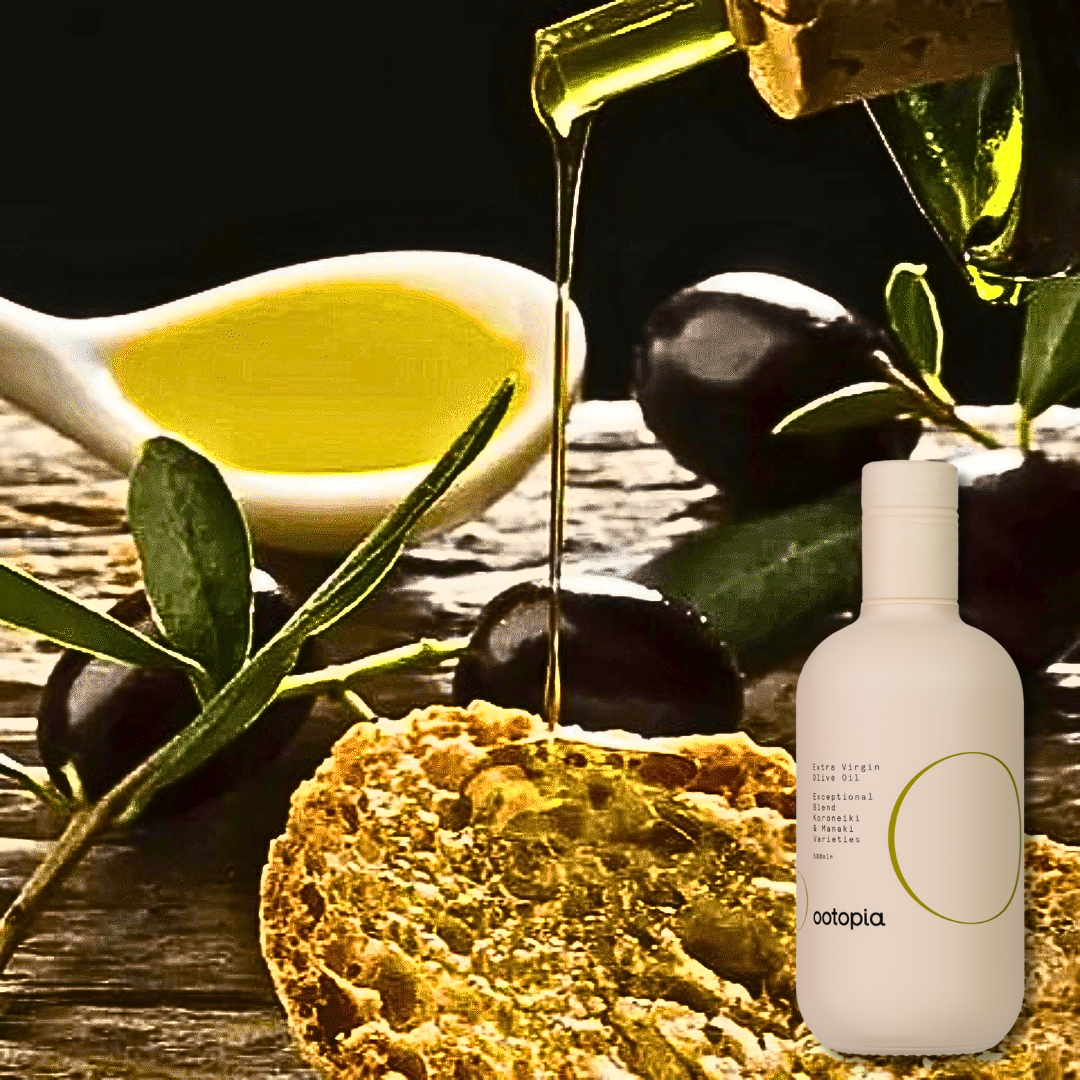 Pouring extra virgin olive oil into a spoon over a glass bowl; Ootopia bottle (Koroneiki & Manaki) on a rustic table.